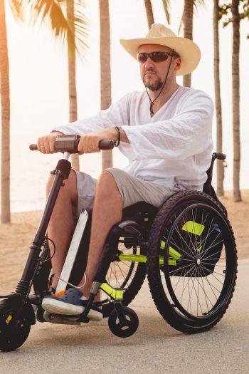 Disabled man in a wheelchair with electric scooter on the beach. Concept background
